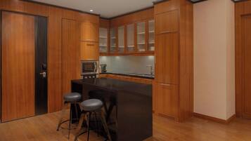 A modern kitchen with wooden cabinets, a black island with bar stools, and a built-in oven.
