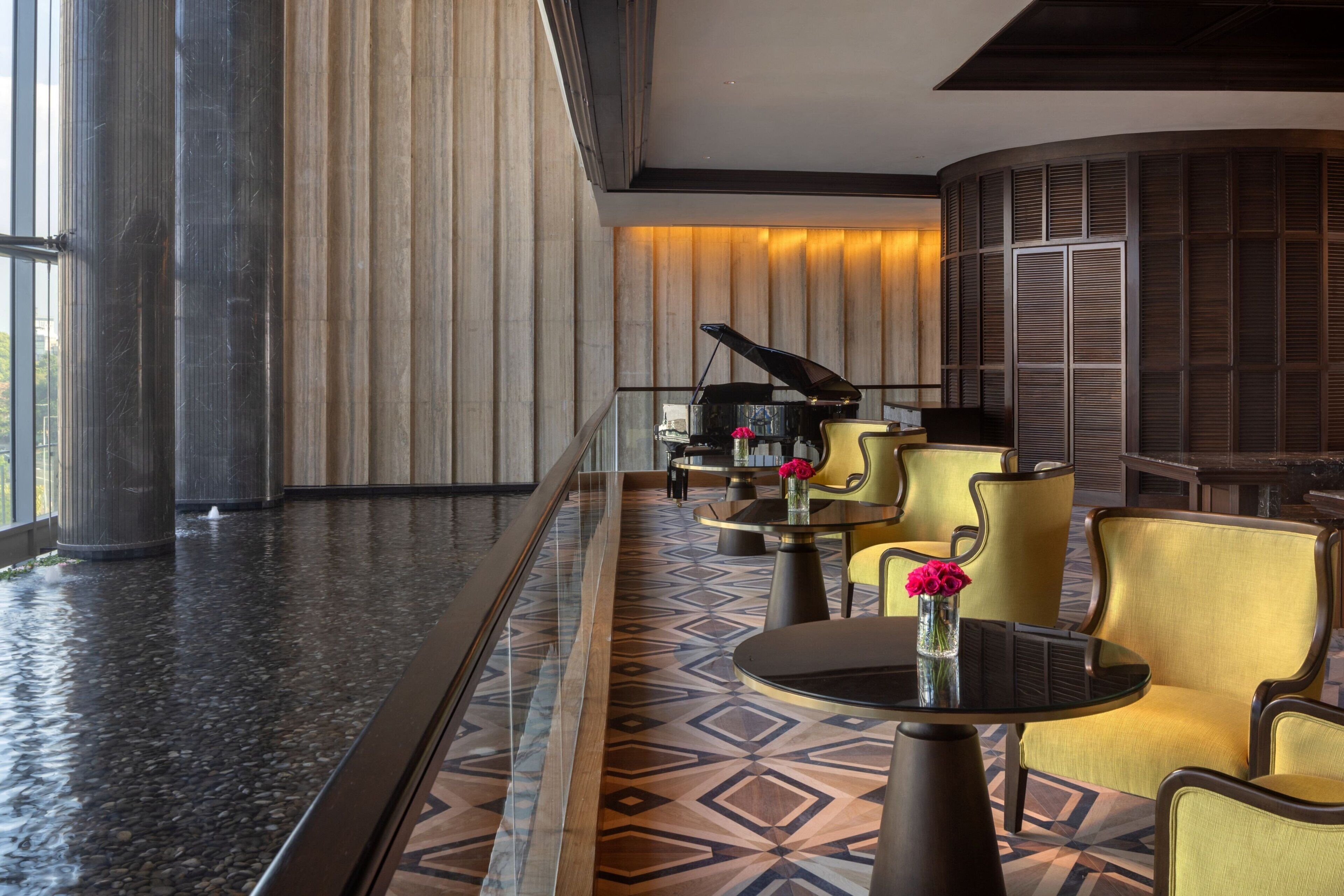 A modern lobby with a piano, yellow chairs, and a patterned floor.