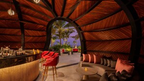 An interior with a curved ceiling, a bar area, seating, and a view of palm trees. - ITC Ratnadipa, a Luxury Collection Hotel, Colombo (Colombo)
