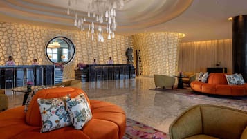 A lobby with a modern design, featuring a reception desk, seating areas, and a decorative wall with a geometric pattern.