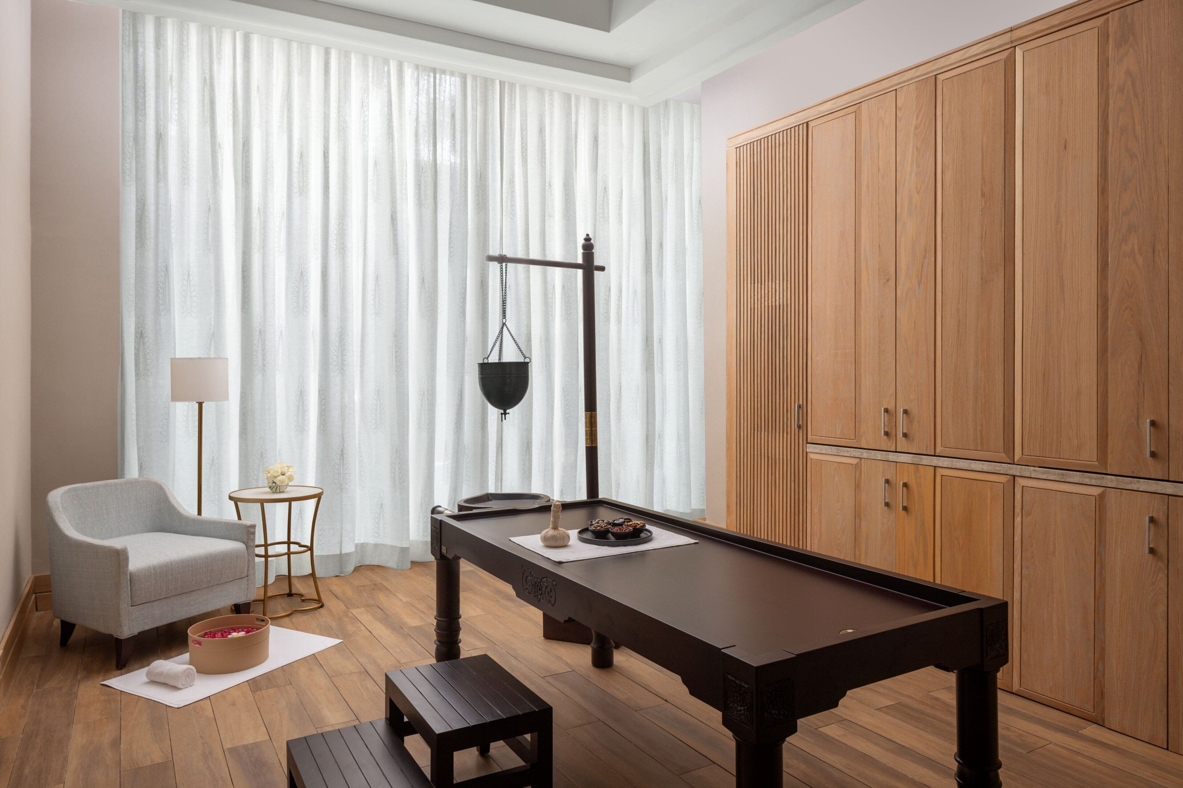 Een kamer met een pooltafel, een stoel, een klein tafeltje met een lamp en een grote houten kast.