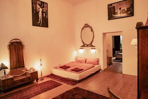 Une chambre à coucher comprenant un lit, un miroir, une lampe et une porte donnant sur une autre pièce.