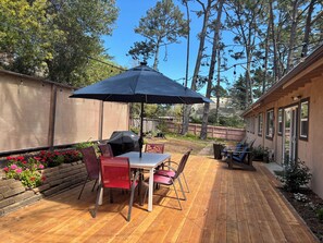 A patio with a table and chairs, a barbecue grill, and a large umbrella. -  Gracious 3-bedroom Pebble Beach Home in Quiet, Convenient Wooded Area (Del Monte Forest)