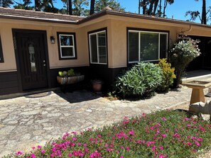 A house with a stone-paved entrance, a black door, and a window with shutters. -  Gracious 3-bedroom Pebble Beach Home in Quiet, Convenient Wooded Area (Del Monte Forest)