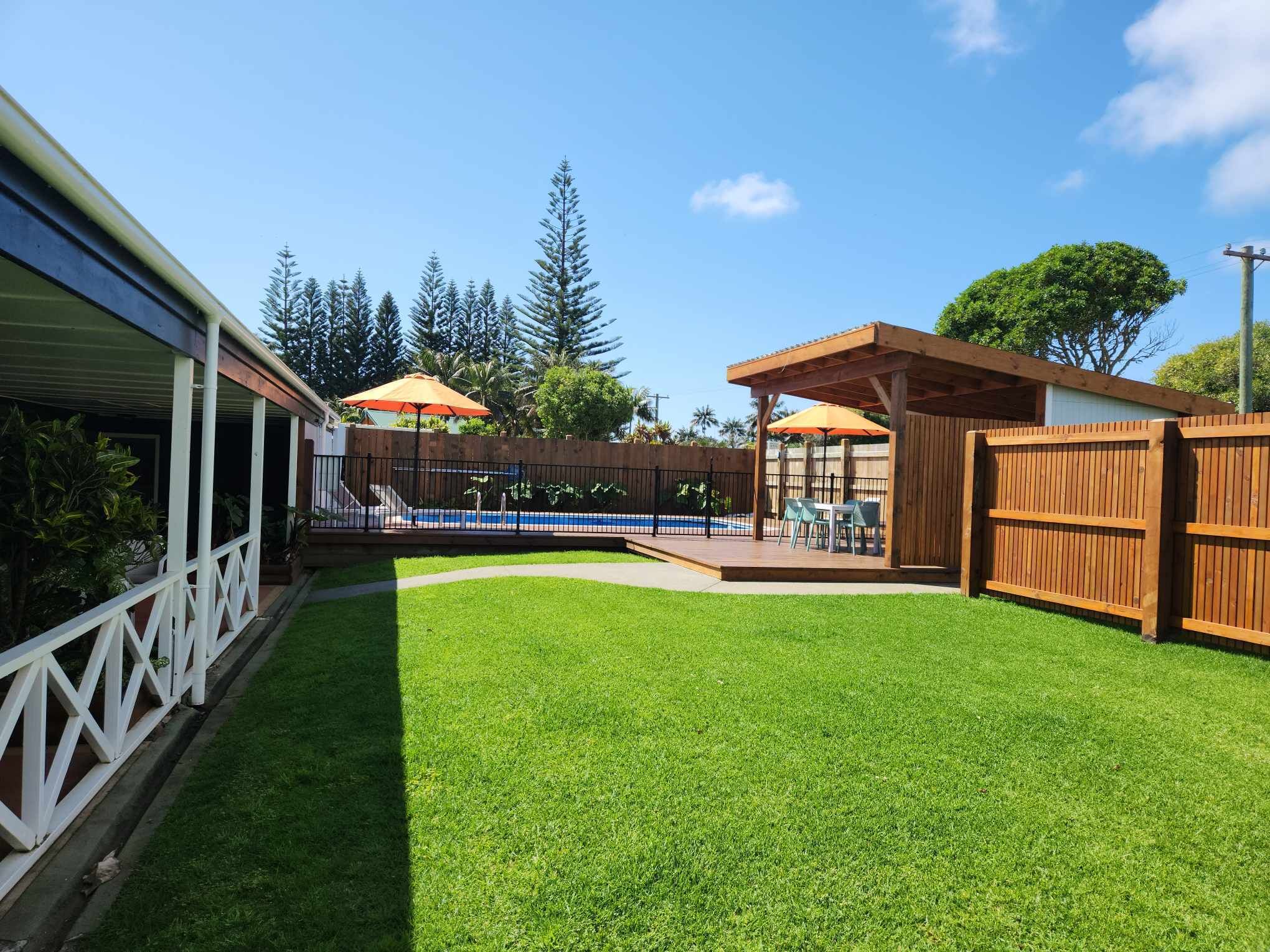 Un patio trasero con piscina, terraza de madera y zona de patio cubierta.
