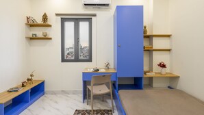 Une pièce de taille modeste, comprenant un bureau, une chaise et des étagères.