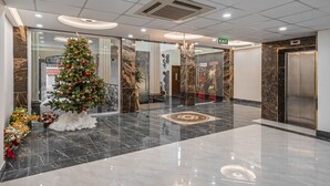Un hall d’entrée moderne, décoré d’un sapin de Noël, doté d’un sol en marbre et d’un ascenseur.