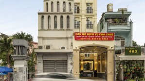 Un hôtel à plusieurs étages, doté d’une entrée imposante, d’une enseigne et d’un réservoir d’eau sur le toit.