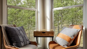A corner room with two leather chairs, a wooden side table, and a view of trees through large windows. - 2BR cabin w/ hot tub & workspace (Hedgesville)