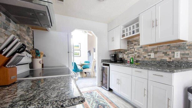 A kitchen with white cabinets, granite countertops, and a patterned rug. - Cheerful 2 Bedroom Home near Virginia Wesleyan (Virginia Beach)