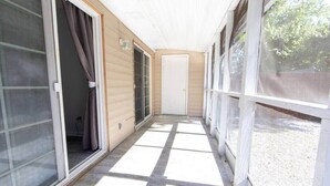 A covered corridor with sliding glass doors, a white door at the end, and a tiled floor. - Cheerful 2 Bedroom Home near Virginia Wesleyan (Virginia Beach)