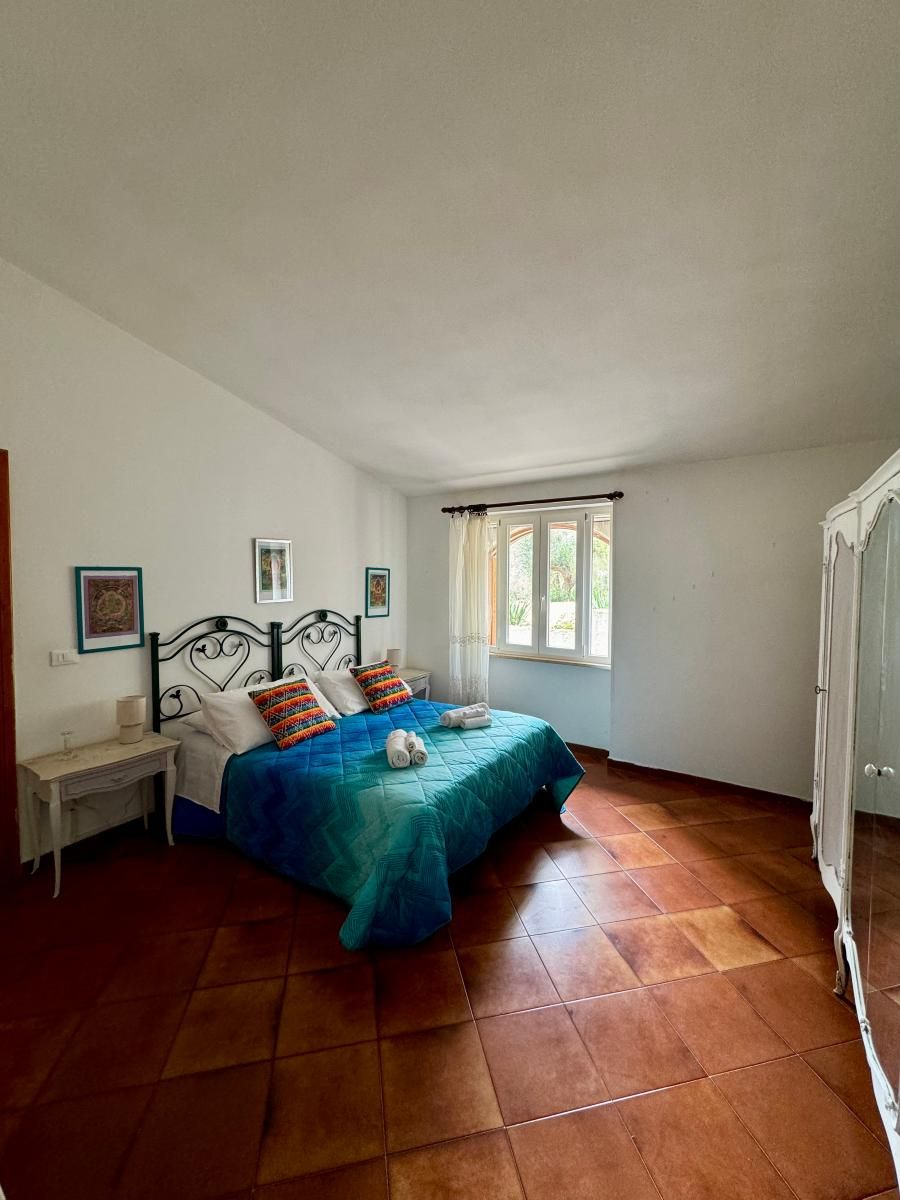 A bedroom with a bed, a nightstand, a wardrobe, and a window with curtains.