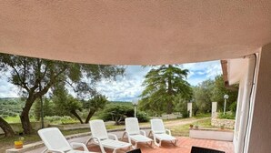 An outdoor patio with a table and chairs, a brick floor, and a view of trees and hills. - Capivento   typical Apulian trullo in the countryside (CEGLIE MESSAPICA)