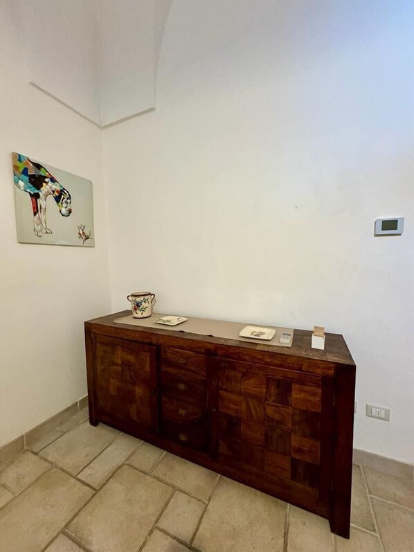 A room with a wooden cabinet, a small table, and a wall-mounted painting.