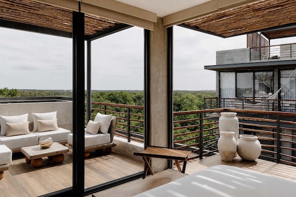 Een modern balkon met een bank, bijzettafeltje en decoratieve vazen.