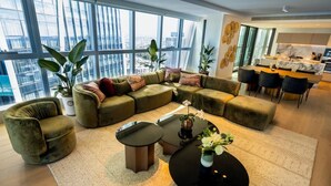A modern living room with a sectional sofa, a round coffee table, and a dining area with a kitchen in the background.
