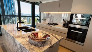 A modern kitchen with a large island, built-in oven, and a view of the city.