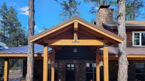 A cabin with a stone exterior, wooden porch, and a chimney. - Lone Star Lodge in Whispering Pines w/ Mountain View - Epic Pickleball Fun!
 (Payson)