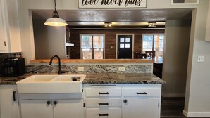 A kitchen with a granite countertop, white cabinets, a black faucet, and a sign above stating "love never fails". - Lone Star Lodge in Whispering Pines w/ Mountain View - Epic Pickleball Fun!
 (Payson)