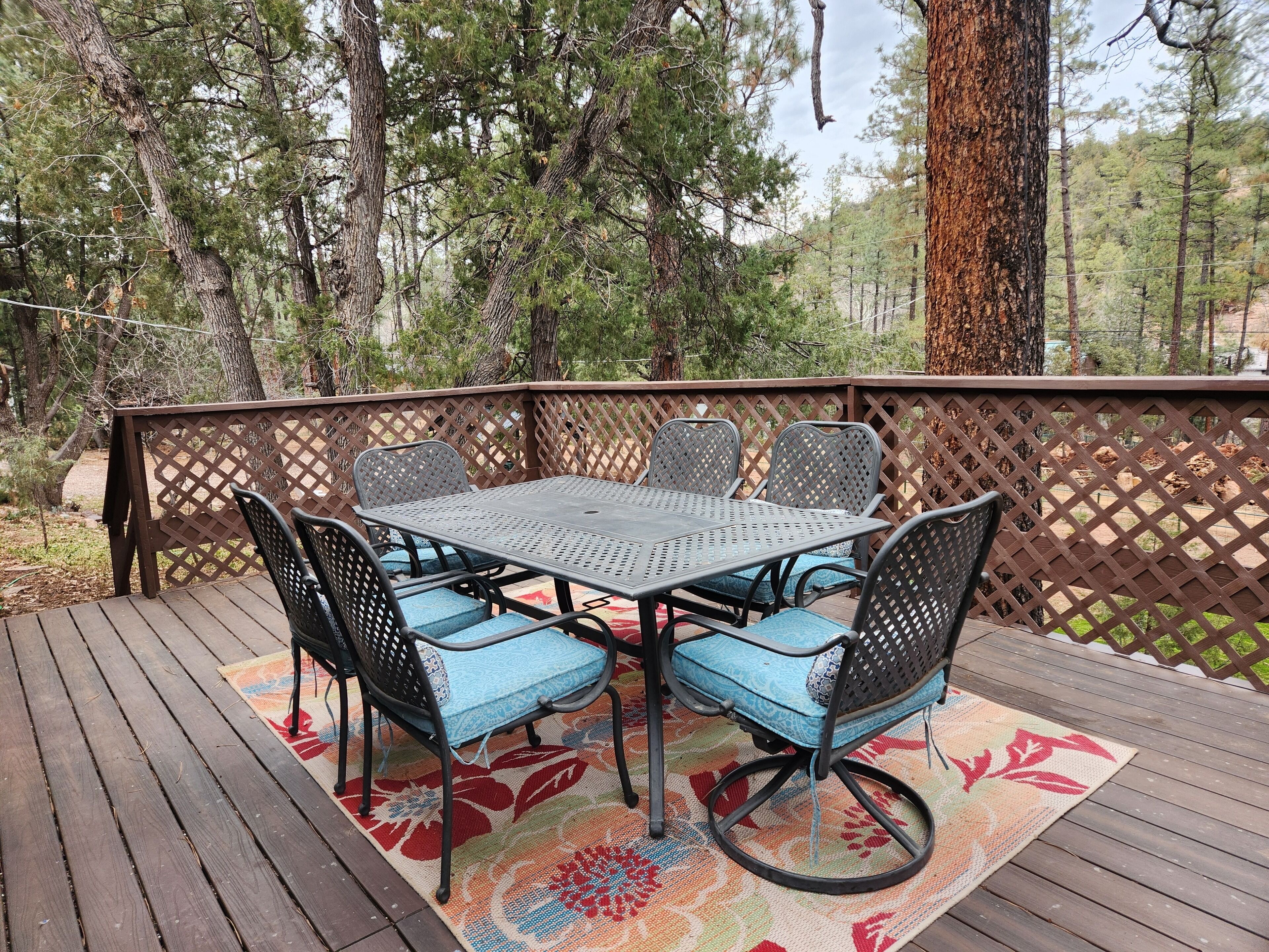 A deck with a table and chairs, surrounded by a wooden fence and trees.