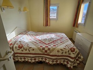 A bedroom with a bed, a window, a radiator, and a dresser.