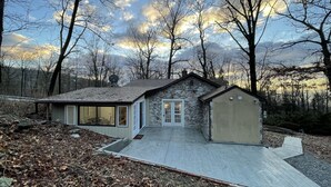 A stone house with a large window and a garage. - Entire Mountain Cottage Near Scenic Hiking Trails, Your Getaway Retreat! (Smithsburg)