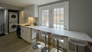 A modern kitchen with a marble countertop, built-in appliances, and a large window. - Entire Mountain Cottage Near Scenic Hiking Trails, Your Getaway Retreat! (Smithsburg)