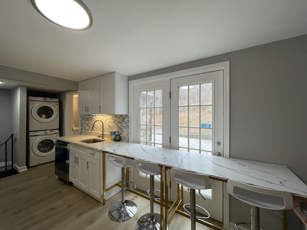A modern kitchen with a marble countertop, built-in appliances, and a large window.