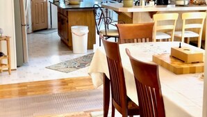A modern kitchen with wooden cabinets, a dining area with a table and chairs, and a refrigerator. - SkyGazers Delight. One of the Safest areas in Bloomington. Super easy access!! (Bloomington)