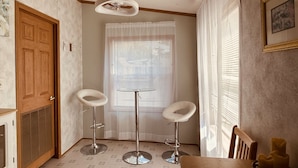 A room with two bar stools, a wooden table, a ceiling fan, and a window with blinds. - SkyGazers Delight. One of the Safest areas in Bloomington. Super easy access!! (Bloomington)