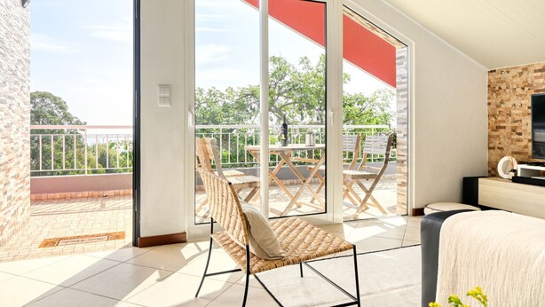 A room with a balcony, a wicker chair, a bed, and a TV. - Cantinho da Mikaela, a Home in Madeira (Ponta do Sol)