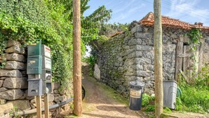 A stone building with a tiled roof, a stone wall, and a pathway leading to it. - Cantinho da Mikaela, a Home in Madeira (Ponta do Sol)