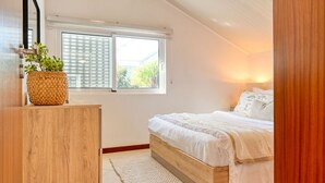 A bedroom with a bed, a window, a bedside table with a plant, and a wall-mounted lamp. - Cantinho da Mikaela, a Home in Madeira (Ponta do Sol)