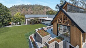 Une maison moderne dotée d’un vaste patio, d’une grande terrasse et offrant une vue sur une colline boisée.