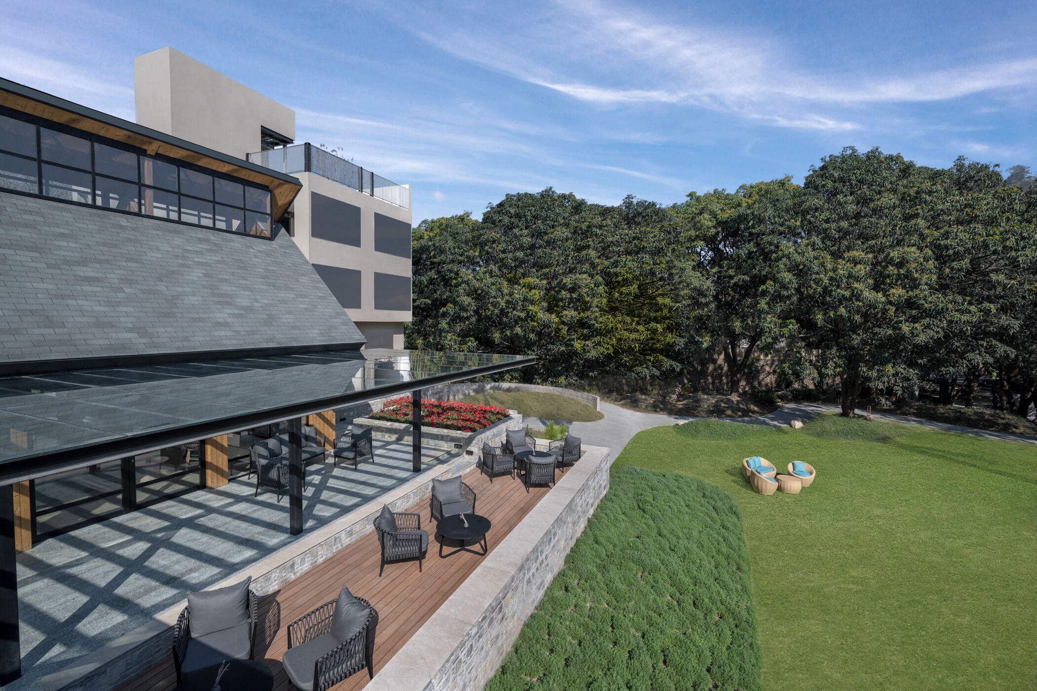 A modern outdoor seating area with a glass balustrade, wooden deck, and outdoor furniture.