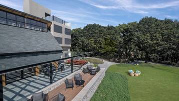 Una moderna zona de estar al aire libre con barandilla de cristal, cubierta de madera y mobiliario exterior.