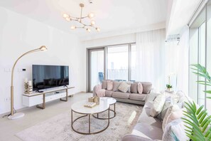 Un salon moderne avec un canapé, une table basse, un téléviseur et une lampe sur pied.