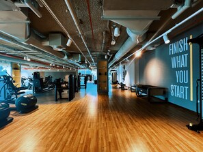 A gym with exercise equipment, wooden flooring, and motivational wall art.