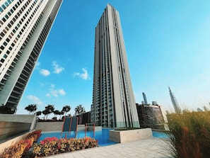 Un immeuble moderne de grande hauteur doté d’une piscine et d’un espace paysager.