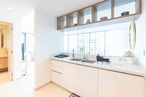A modern kitchen with white cabinets, a wooden countertop, and a window above the sink.