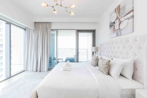 Ein modernes Hotelzimmer mit einem großen Bett, einer Chandelier, einem Balkonblick und einem großen Fenster.