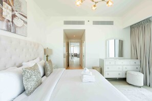 A modern bedroom with a large bed, a dresser, and a mirror.