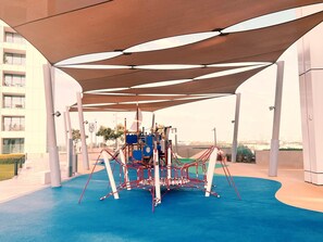 An outdoor play area with a climbing structure and a shaded seating area.