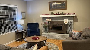 A living room with a fireplace, a blue armchair, a round coffee table, and two sofas. - The Tangerine Door (Lewiston)