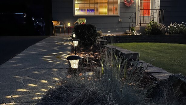 A house with a well-lit front porch, a wreath on the door, and a landscaped front yard. - The Tangerine Door (Lewiston)