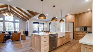 Une cuisine spacieuse avec des meubles en bois, un îlot central et des luminaires suspendus.