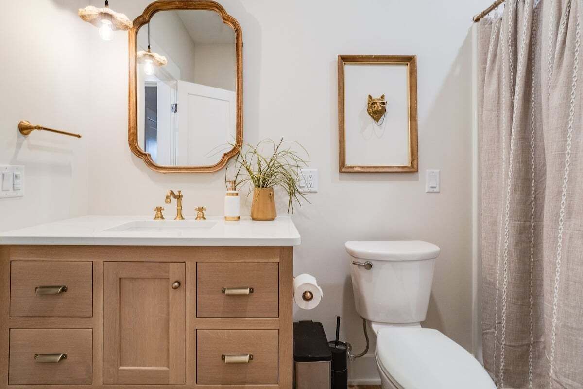A bathroom with a wooden vanity, a toilet, a framed picture, and a mirror.