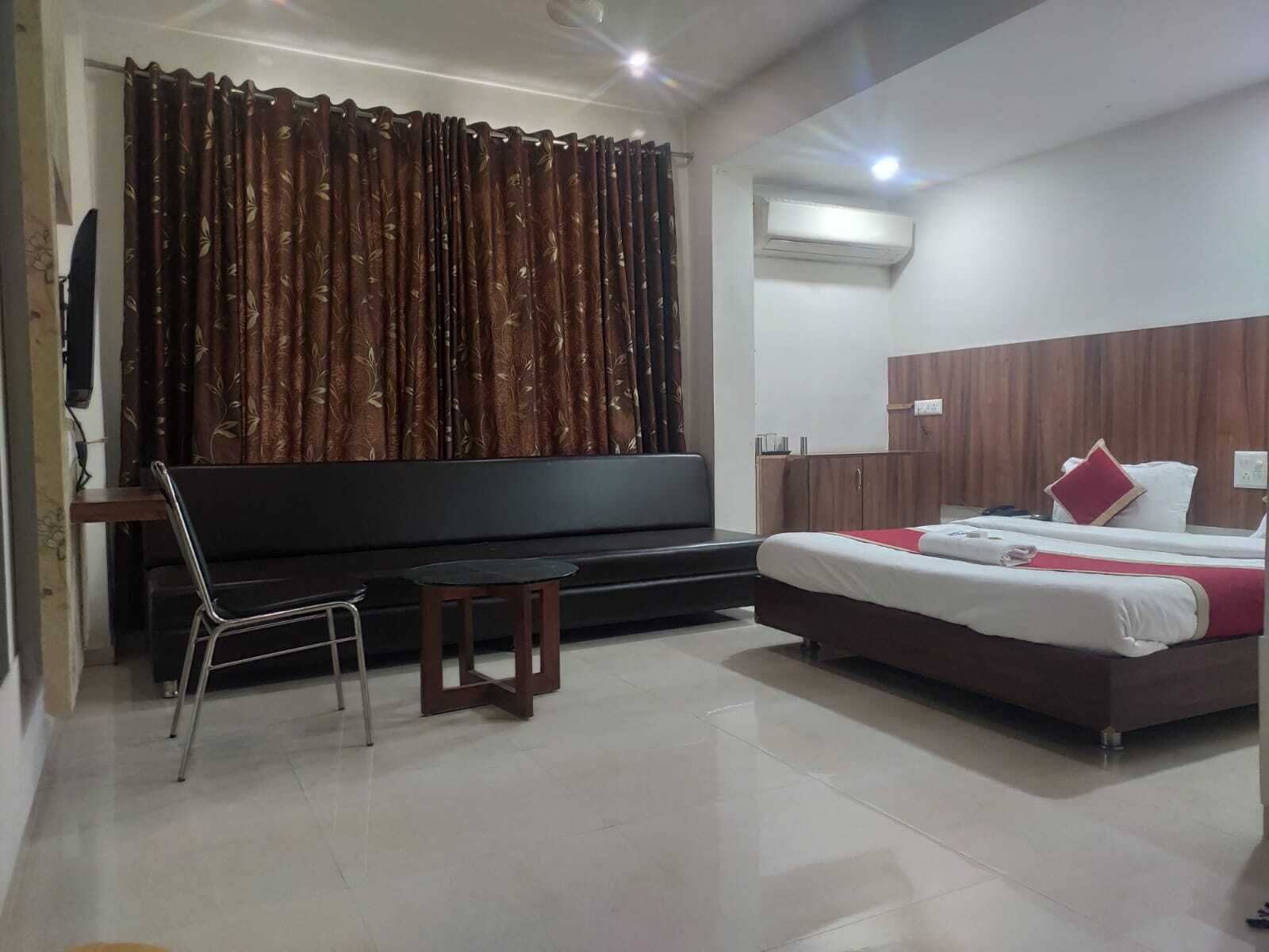 A hotel room with a bed, a sofa, a small table, and a TV.