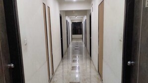Un largo pasillo estrecho con suelo de mármol pulido y puertas a ambos lados.