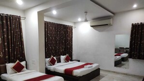 Habitación de hotel con dos camas, ventilador de techo, unidad de aire acondicionado y espejo en la pared.